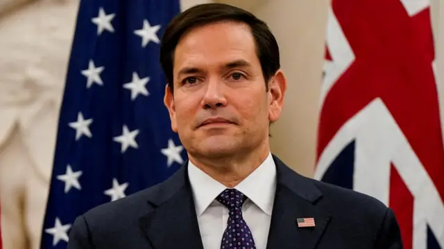 Secretary of State Marco Rubio is pictured standing in front of US and UK flags