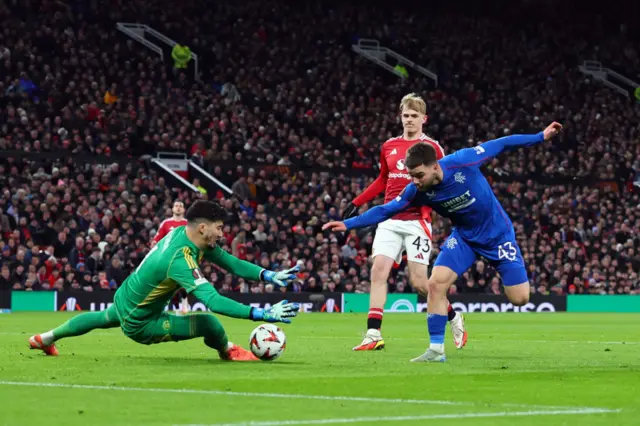 Altay Bayindir of Manchester United saves from Nicolas Raskin of Rangers during the UEFA Europa League 2024/25 League Phase MD7 match between Manchester United and Rangers FC at Old Trafford