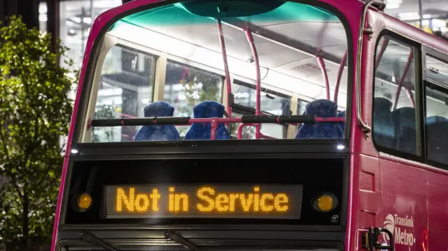 A pink Metro Translink bus with the words 'not in service' illuminated on its front in orange