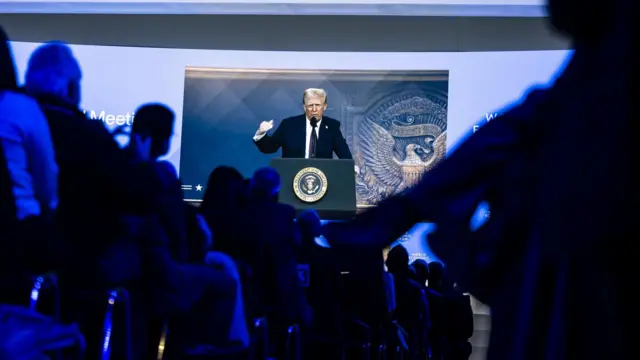 US President Donald J. Trump is shown on a screen as he addresses via remote connection a plenary session in the Congress Hall during the 55th annual meeting of the World Economic