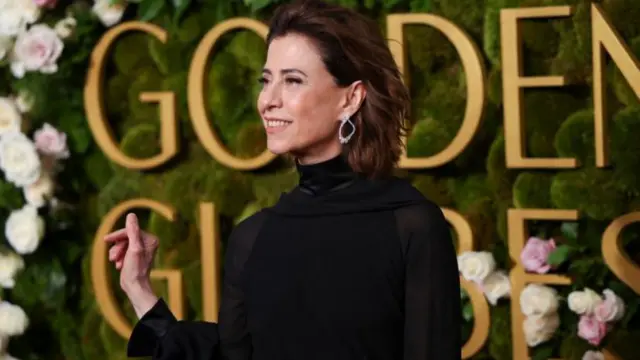 Fernanda Torres in front of a green wall with flowers and Golden Globes written on it