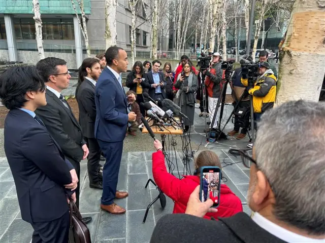 People stand in front of microphones as reports gather around