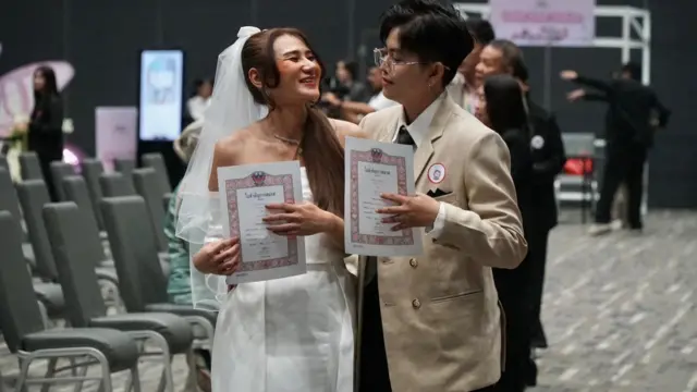 A couple holds their marriage certificates