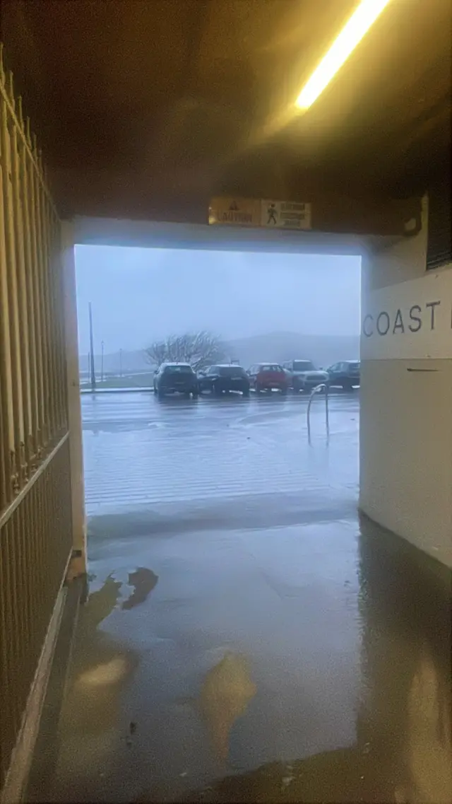 The view out from a tunnel where a car park is drenched by rain