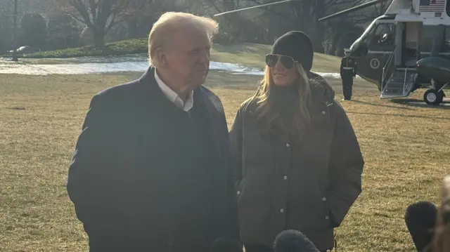 Donald and Melania Trump on the White House lawn before boarding the helicopter behind them.