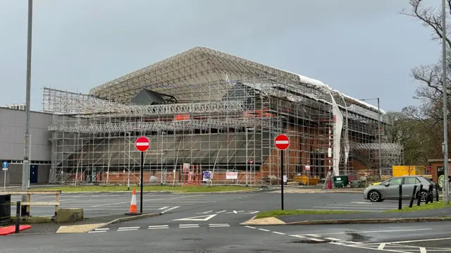 Scaffolding surrounding The Sands Centre in Carlisle where the canopy is bucking and lifting in the hinds winds and sections of sheeting are hanging down from the sides of the building