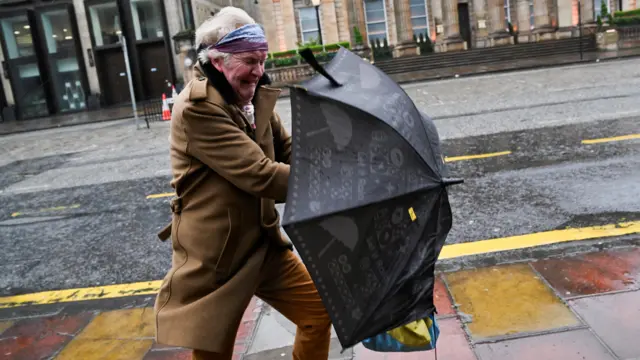 A man struggles with an umbrella in the wind