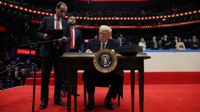 Donald Trump signs an executive order during the inaugural parade inside Capital One Arena