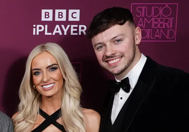 Leanne and Jake in black tie in front of a purple BBC ipayer and Studio Lambert logo