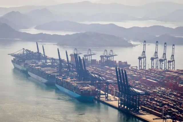 A wide shot of Yantian Port in shenzhen - cranes , containers and misty mountains in the distance