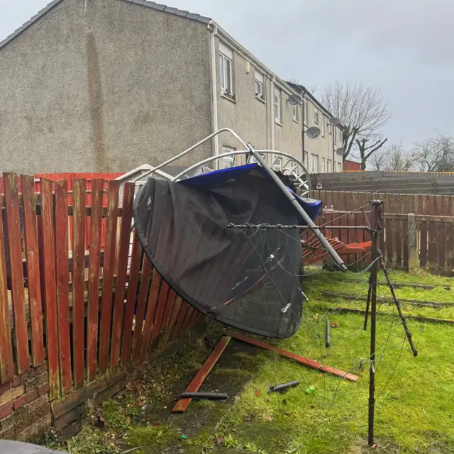 Crumpled trampoline resting on a fence