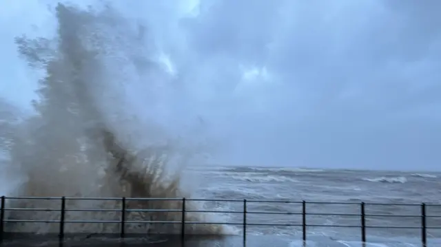 A large wave crashes against the sea wall at Maryport