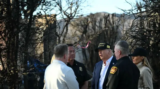 US President Donald Trump and First Lady Melania Trump speak with officials as they tour a fire-affected area in the Pacific Palisades neighborhood of Los Angeles