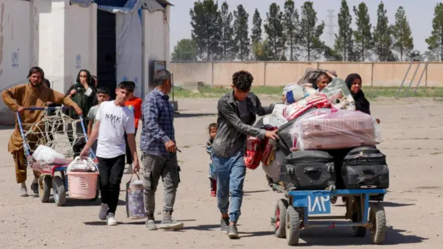 Afghan refugees push carts and carry their belongings