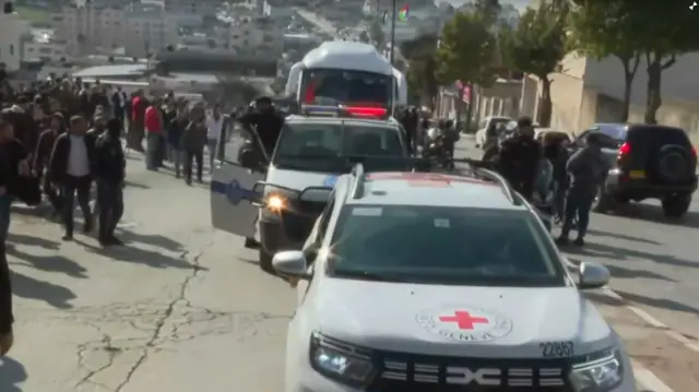 In Ramallah, buses and cars are seen on a road alongside vehicles with sirens.