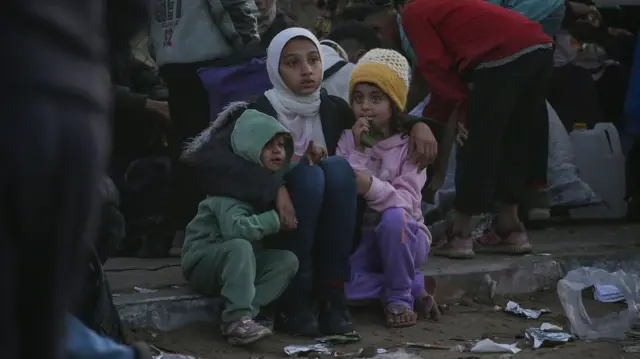 Three girls huddle together in a crowd of people