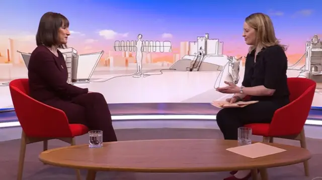 Rachel Reeves (L) listens while sitting in a red chair as Laura Kuenssberg (R) asks her a question while sitting in a matching chair