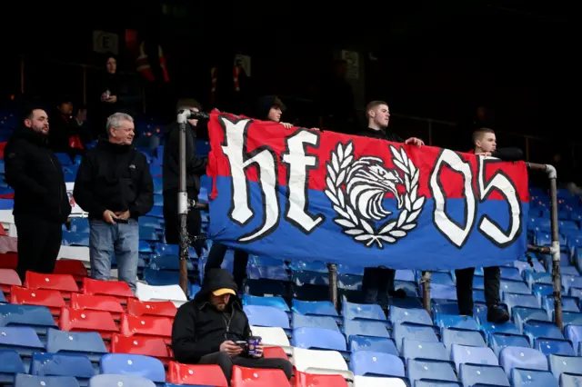 Fans of Crystal Palace, the 'Holmesdale Fanatics', hold a banner reading 'HF05'.