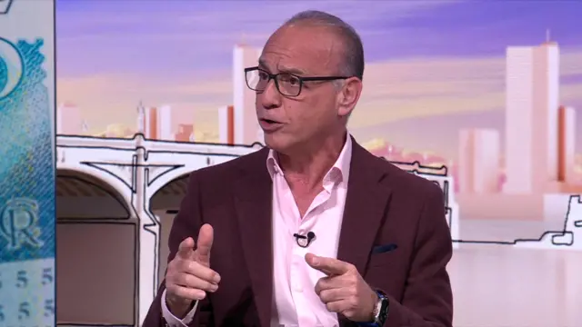 Entrepreneur Theo Paphitis gesturing with his hands while speaking with Sunday with Laura Kuenssberg graphics in background