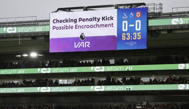 The big screen displays a VAR review message