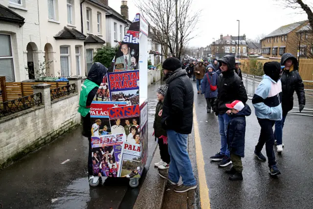 Fans buy match day programmes outside the stadium