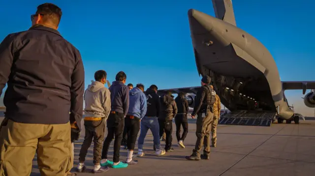 Migrants board a military aircraft