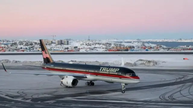 Donald Trump Jr's plane, emblazoned with 'Trump' across the front, at Greenland's Nuuk airport. Ice can be seen on the runway and a snowy landscape behind.