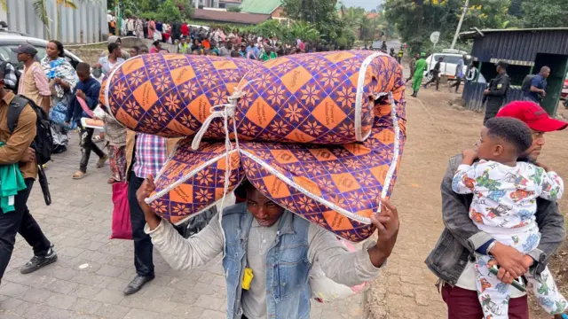 A man carrying a mattress on his head as he leaves Goma