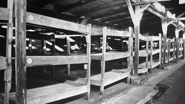 Row of bunk beds in Auschwitz in black and white