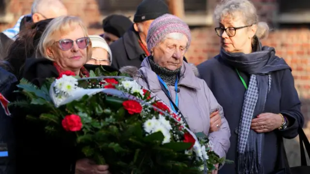 Three women side by side holding a wreath