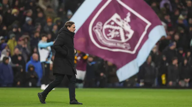 Daniel Farke makes his way to the dugout with a massive Burnley flag in the background