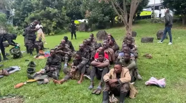 Screengrab showing soldiers seated on grassy bank near border crossing at Gisenyi