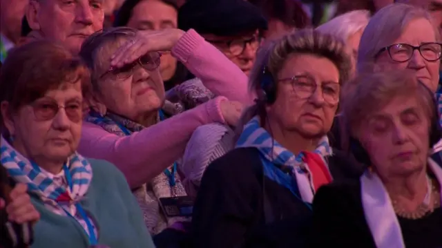 A woman shields her eyes for brightness as she looks ahead