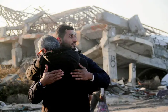 Two men hug in front of ruins in Gaza