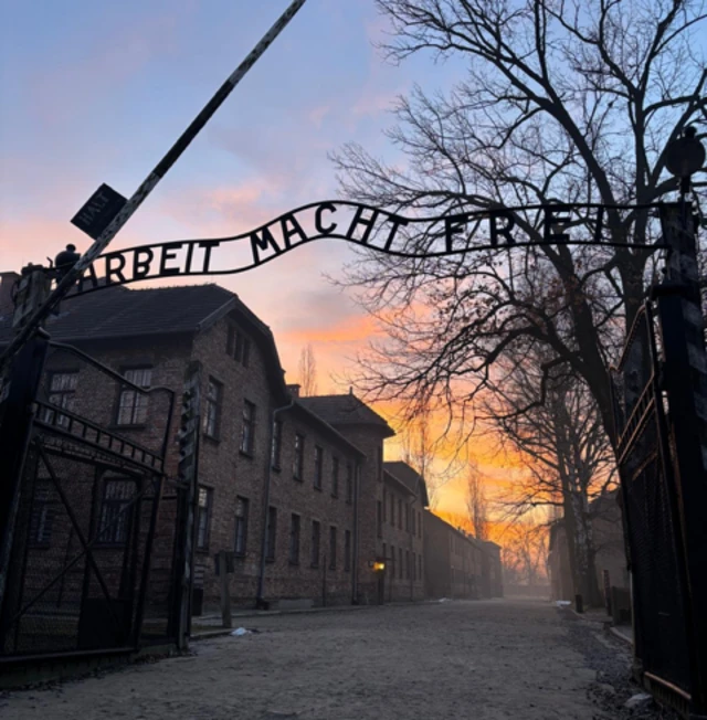 The sign Arbeit Macht Frei with the sun rising in the background