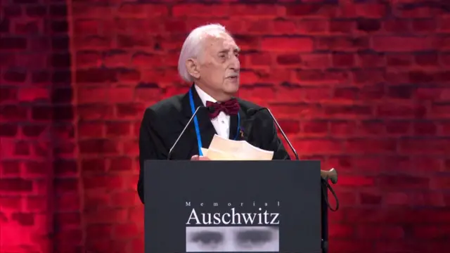 Leon Weintraub, speaking into a microphone, behind a podium