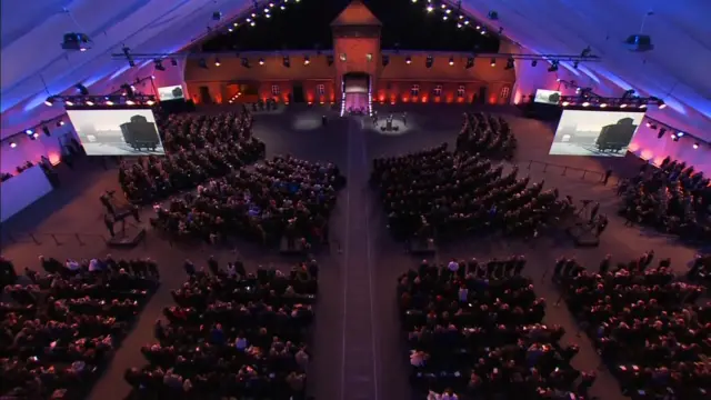 A birds-eye view of inside the tent, people sitting in collections of seats arranged in squares