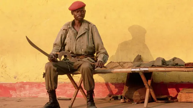 A Congolese soldier sits down while holding two blades