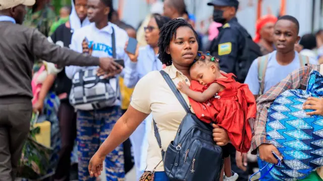 Refugees carry their belongings after crossing the border from Goma in the Democratic Republic of Congo to Gisenyi, Rwanda, 27 January 2025