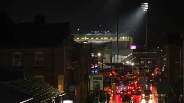 A floodlight illuminates one corner of Turf Moor as the team buses arrive