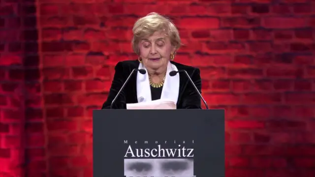 Tova Friedman speaking into microphone behind a podium