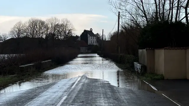 A road in Somerset is seen in the early dawn light with deep flood water covering it