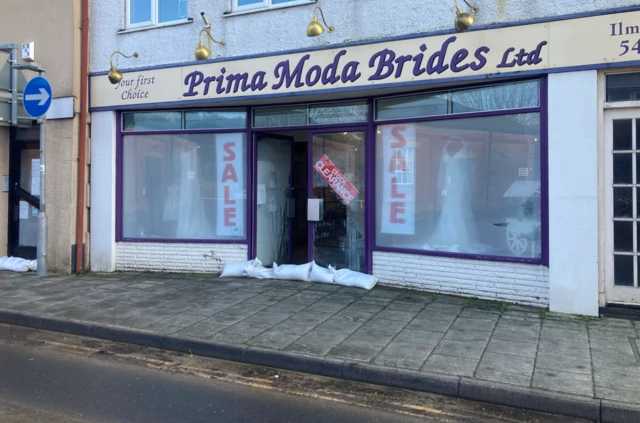 The picture shows the front of the shop.  There is a Stock Clearance sign and sandbags outside the front door