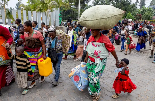 Dozens of people make their way out of Goma holding their belongings