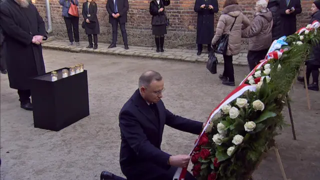 Man kneeling at the base of a wreath in a courtyard