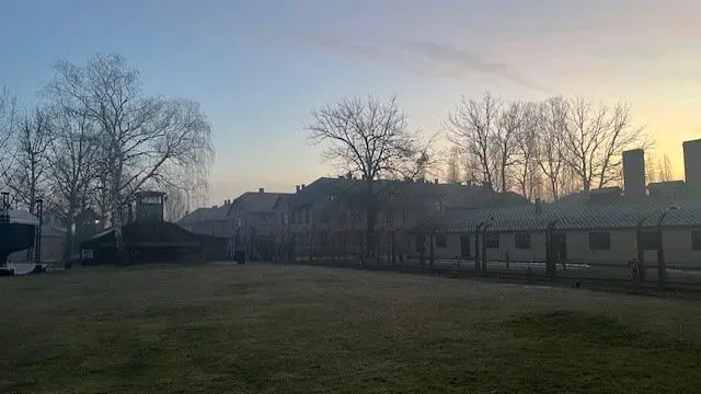 The fence and camp buildings, with the sun rising in the background