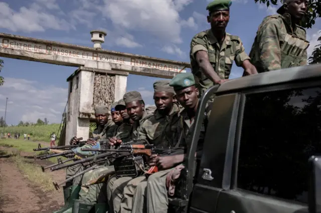 M23 rebels holding rifles on the back of a pick up truck