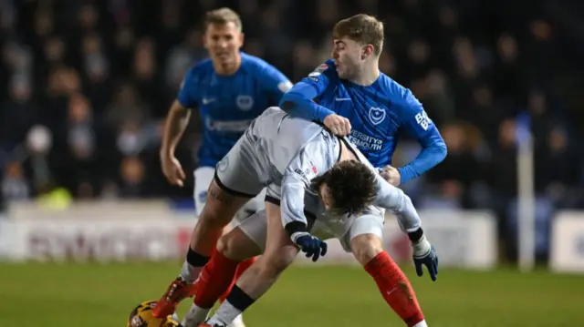 Portsmouth's Zak Swanson bundles Millwall forward Aaron Connolly to the ground