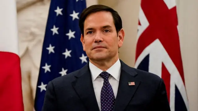 U.S. Secretary of State Marco Rubio looks on behind the flags of the USA and United Kingdom