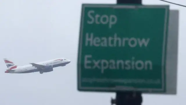 A campaign sign opposing airport development is seen attached to a lamp post as a British Airways passenger plane takes off from Heathrow Airport, Harmondsworth, west London, Britain, January 28, 2025